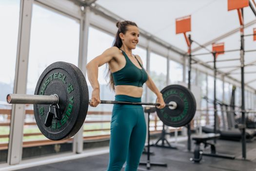 A fit woman lifting a heavy barbell at an indoor gym, showcasing strength and determination.