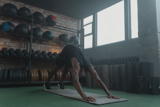 Man performing fitness workout on yoga mat in gym. Focus on strength and body posture.