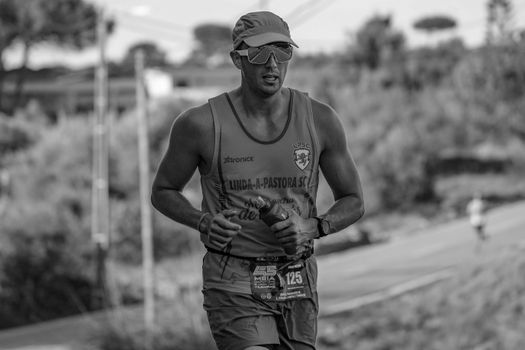 A black and white photo capturing a male runner during an outdoor race.
