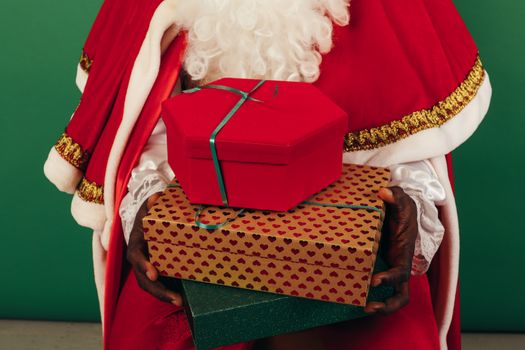 Festive holiday photo of Santa Claus holding wrapped Christmas presents.